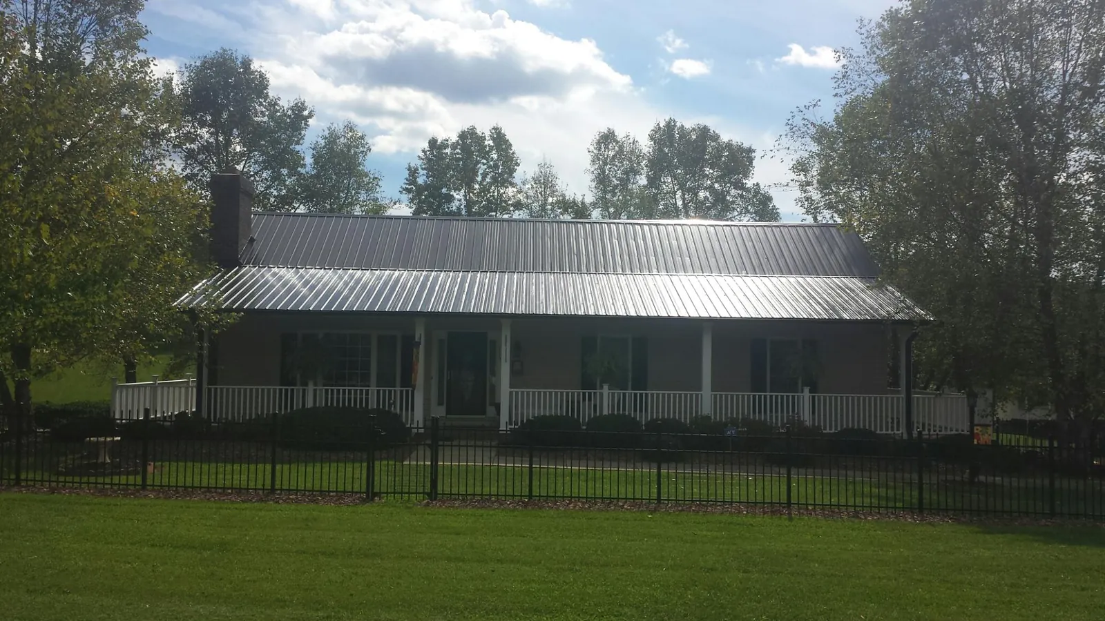 Gray metal roof on a brick ranch with a full width front porch — Gutter Guard Installation work by our crew in Shelbyville